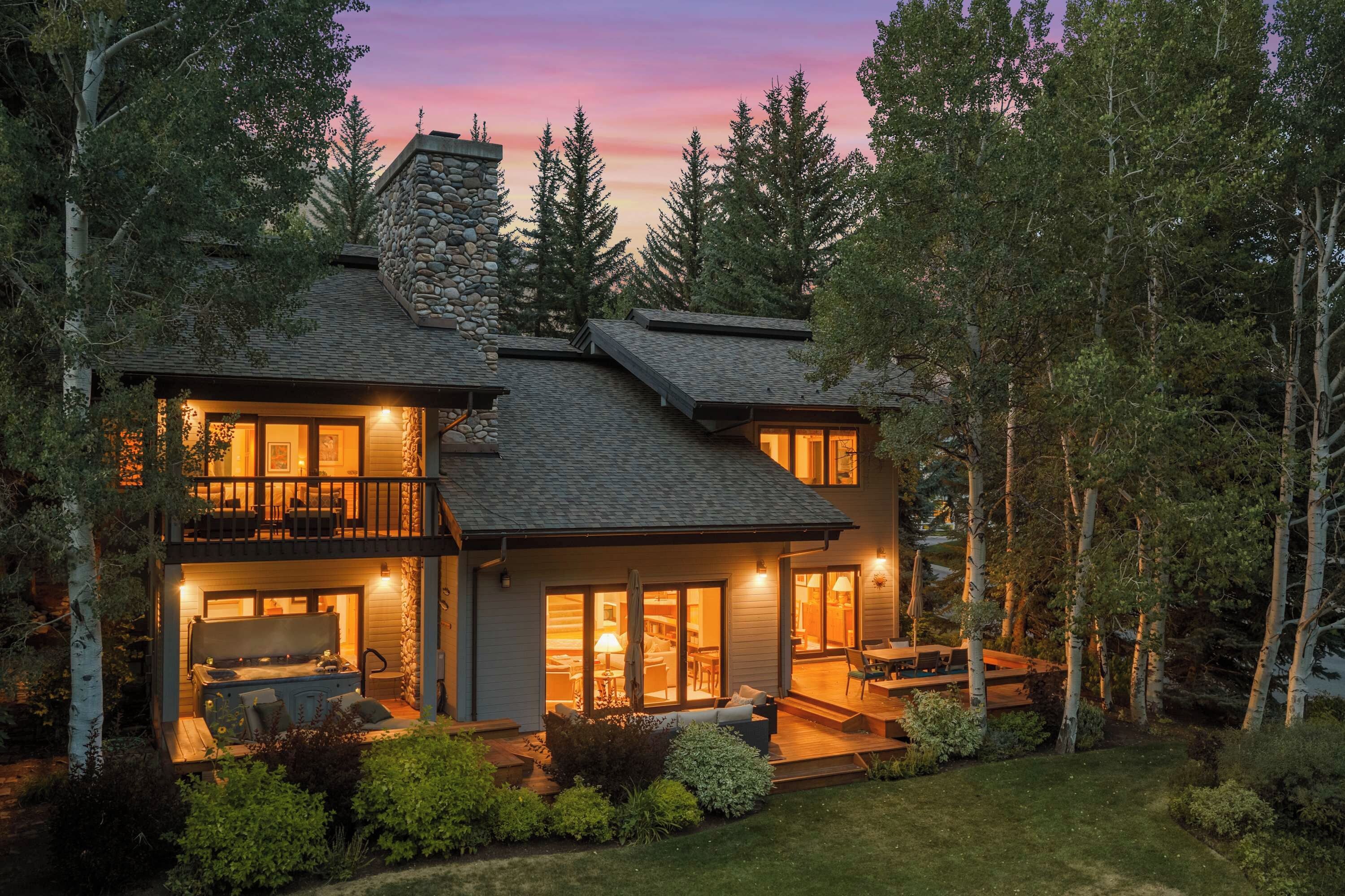 A two-story house with a stone facade, large windows, and a deck.