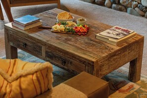 A rustic wooden coffee table with a book, a bowl of salad, and a magazine. - Abode at Guyer Hot Springs, walk to lift, hot tub (Ketchum)