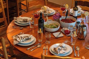 A round wooden dining table set with plates, glasses, cutlery, and a bottle of wine. - Abode at Guyer Hot Springs, ski slope views, walk to lift, hot tub (Ketchum)