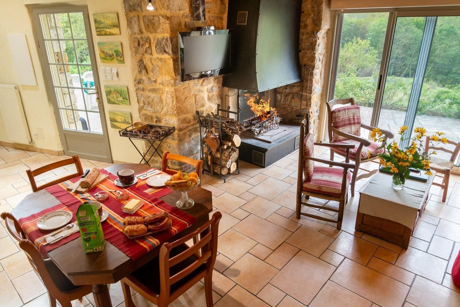 Un comedor con pared de piedra, chimenea y televisor montado en la pared.