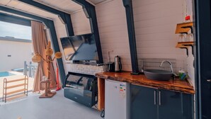 Una cocina moderna con una televisión de pantalla plana, un lavabo y un refrigerador.