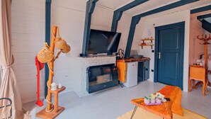 Una habitación acogedora con chimenea, televisión y una pequeña cocina.