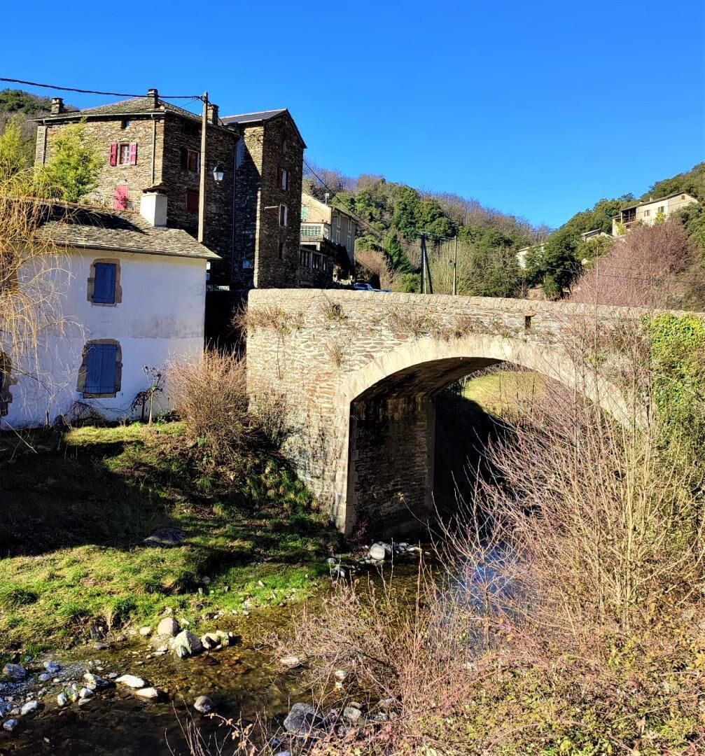 Un pont de pierre enjambe un ruisseau, avec des bâtiments de chaque côté.