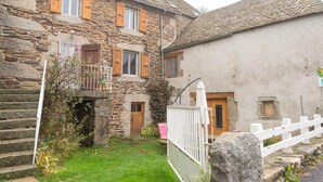 A stone building with a small balcony, a wooden door, and a white fence. - Chez Baptiste - SAINT-PIERRE-DE-NOGARET (SAINT-PIERRE-DE-NOGARET)