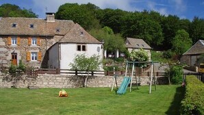 A stone house with a white exterior, a swing set, and a small yellow toy car in the yard. - Chez Baptiste - SAINT-PIERRE-DE-NOGARET (SAINT-PIERRE-DE-NOGARET)
