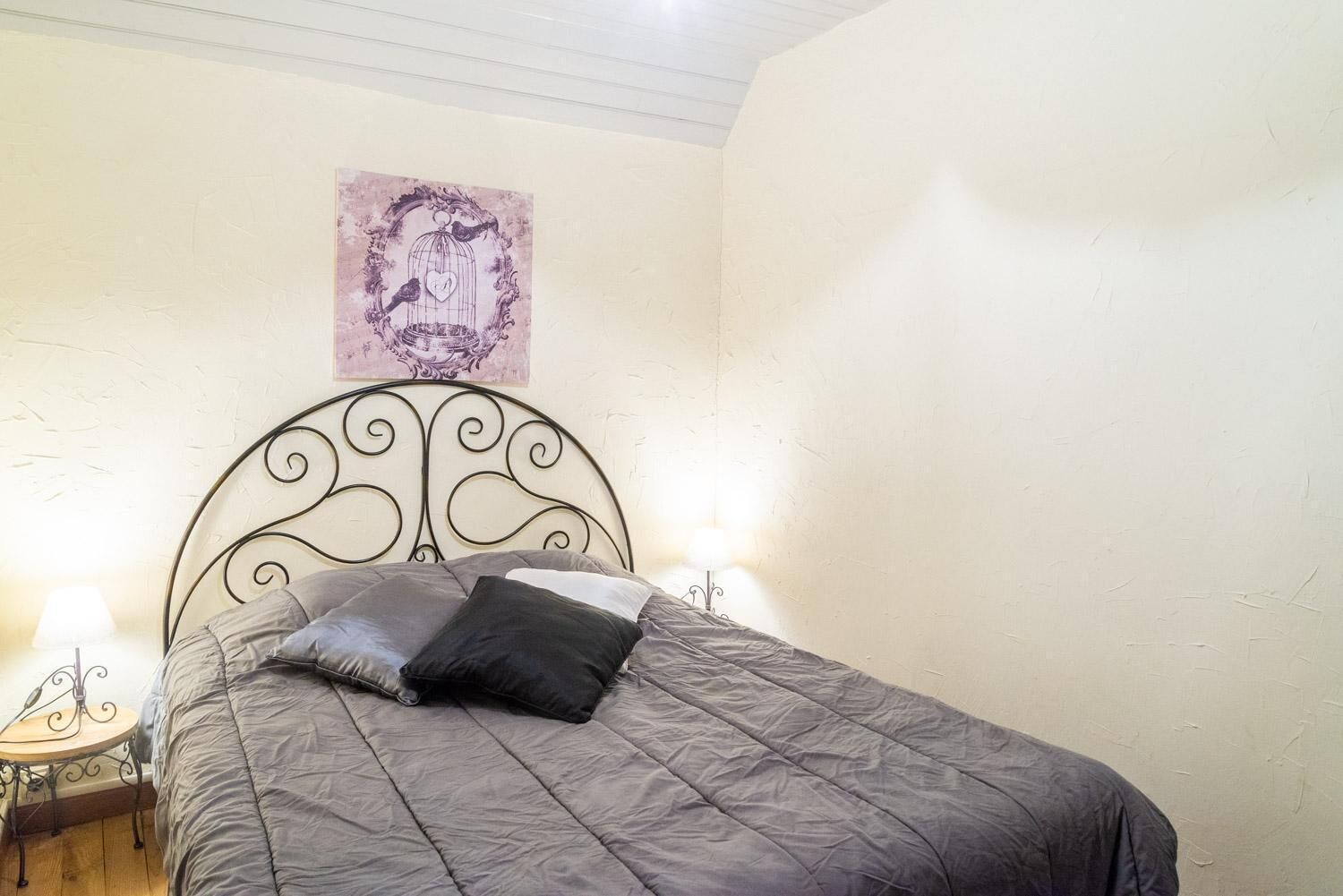 A single bed with a metal headboard, a bedside table with a lamp, and a wall-mounted artwork.