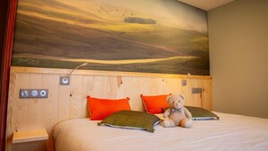 Ein Schlafzimmer mit einem großen Landschaftsbild, einem Bett mit zwei Kissen, einem Teddybären und einem Nachttisch mit einer Lampe.