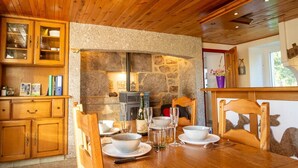 Ein Zimmer mit Holzwänden, einer Steinwand, einem Kamin und einem Esstisch, gedeckt mit Tellern, Gläsern und einer Flasche.