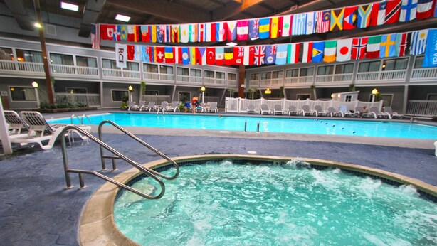 Una piscina con una scaletta metallica, sedie a sdraio e bandiere appese.