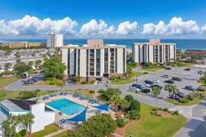 A high-rise hotel with a swimming pool, parking lot, and ocean view. - Enclave 701a- Shore Fun (Destin)