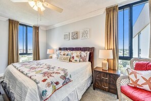 A bedroom with a bed, nightstands, a chair, and a ceiling fan. - Enclave 701a- Shore Fun (Destin)