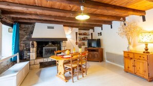 A rustic interior with a stone fireplace, wooden dining table, and a television on a wooden cabinet. - Gîtes de France 3/5 pers in Saint-Chély-du-Tarn (SAINT-CHELY-DU-TARN)