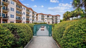 A gated entrance to a residential building complex with multiple balconies and a clear sky. - Emerald Waters 301- Saltwater Therapy (Miramar Beach)