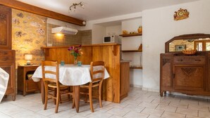 Ein Essbereich mit einem Tisch für vier Personen, Holzkästen, einer weißen Tischdecke und einer Vase mit Blumen.