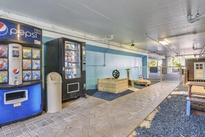 A vending machine area with a Pepsi machine, a trash bin, and wooden play structures. - Destin West Gulfside 311- Paradise Gulfside (Fort Walton Beach)