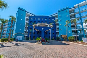 A multi-story hotel with a blue facade, a central courtyard with plants, and balconies. - Destin West Gulfside 311- Paradise Gulfside (Fort Walton Beach)
