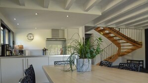 Una cucina moderna con zona pranzo, una scala in legno e un orologio appeso al muro.