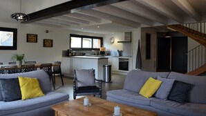 Un soggiorno moderno con divani grigi, un tavolino in legno e una cucina sullo sfondo.
