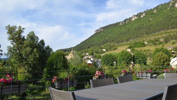 Una terrazza con tavoli e sedie, affacciata su un pendio con case e una chiesa.