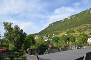A terrace with tables and chairs, overlooking a hillside with houses and a church. - Gîte Les Falaises in Barjac (BARJAC)