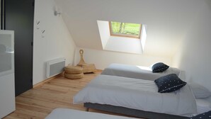 Camera da letto con due letti, un lucernario, una piccola finestra e pavimento in legno.