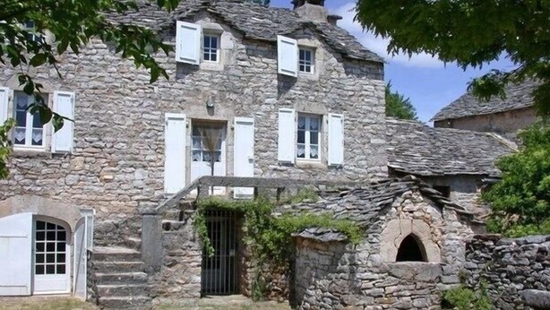 Un bâtiment en pierre doté de nombreuses fenêtres, d’une porte et d’une petite fenêtre en arc de cercle.