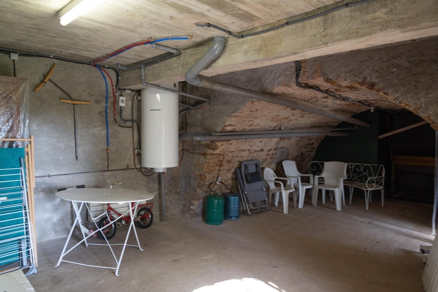 A room with a white heater, a table, chairs, and a visible water tank.