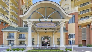 Ein Hotel Eingang mit einem Schild, das 'Emerald Grande' zeigt, mit klassischer Architektur, Säulen und einem gewölbten Dach.