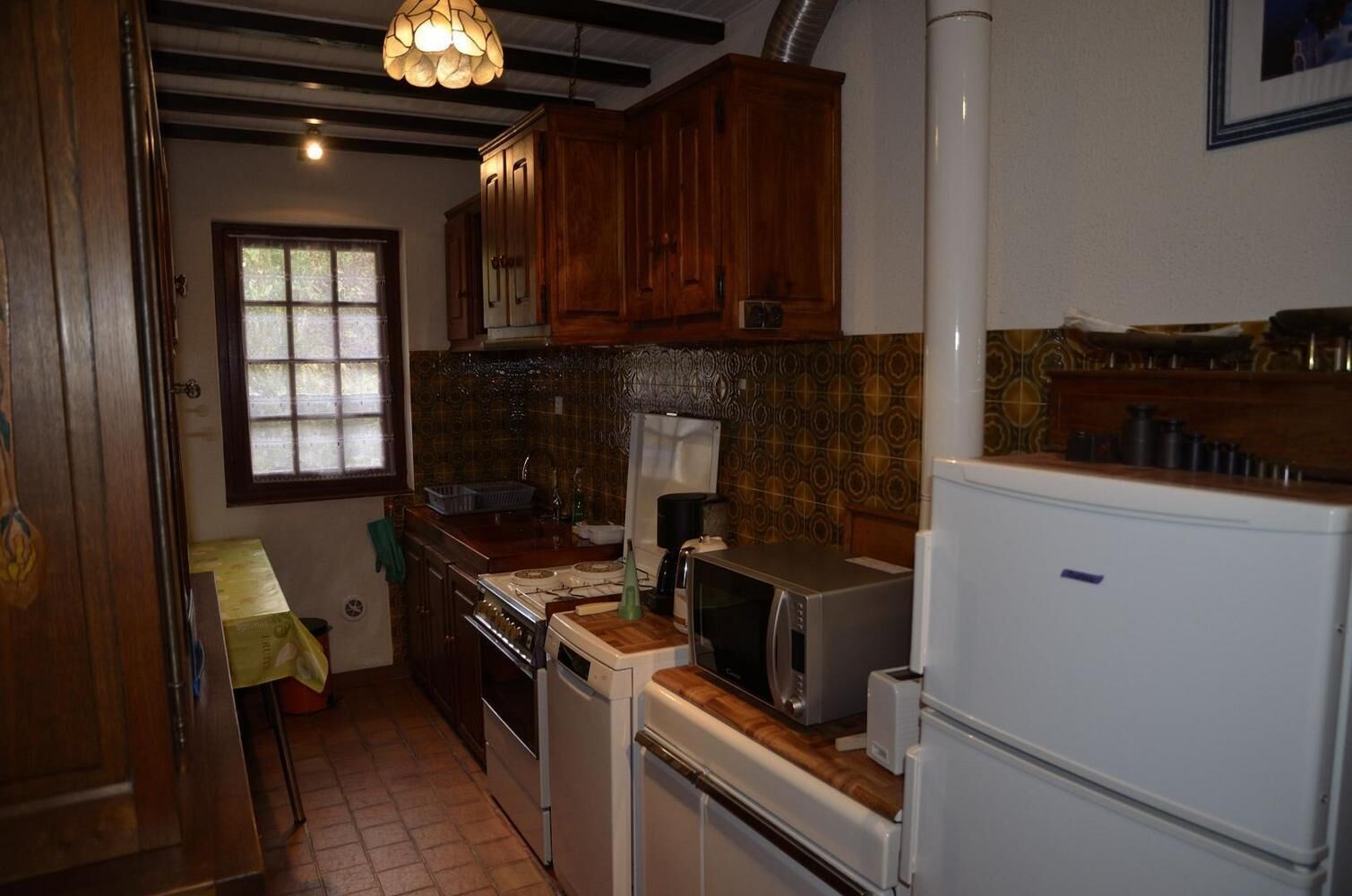 A kitchen with wooden cabinets, a stove, a microwave, and a refrigerator.