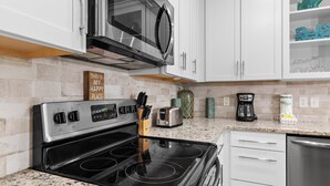 Una cocina con estufa, microondas y armarios blancos.