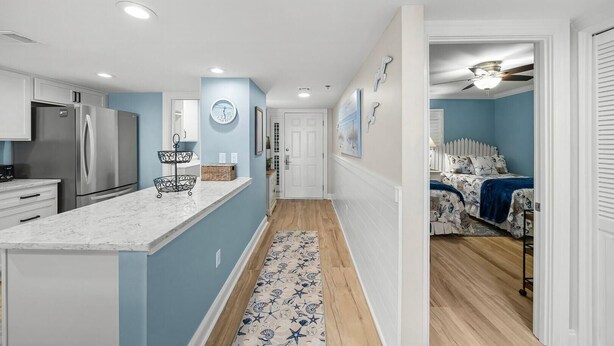 A modern kitchen with a central island, a dining area with a table and chairs, and a bedroom with a bed and a ceiling fan. - Destin Towers 122- Destin Dream (Destin)