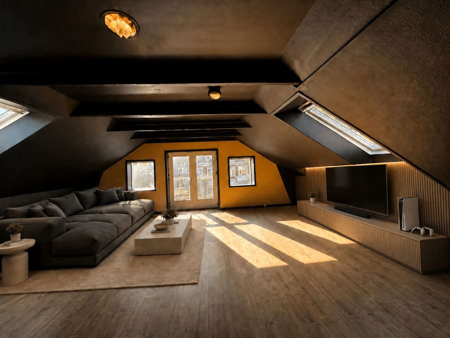 Un moderno apartamento tipo loft con un sofá grande, un televisor de pantalla plana y piso de madera.
