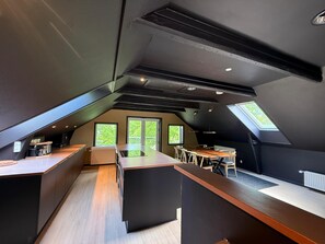 Una cocina moderna con una isla central, una zona de comedor con mesa y sillas, y un tragaluz grande.
