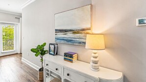 A hallway with a white console table, a lamp, a framed painting, and a potted plant. - Driftwood Townhomes #1- Beachwaves (Miramar Beach)