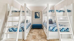 A room with bunk beds, a blue ottoman, and a framed picture on the wall. - Driftwood Townhomes #1- Beachwaves (Miramar Beach)