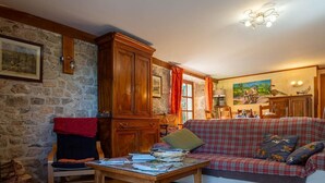 A cozy living room with a sofa, wooden cabinet, stone wall, and a painting. - Gîte La Narce - TERMES (TERMES)