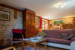 Un salon chaleureux avec un canapé, un meuble en bois, un mur en pierre et un tableau.