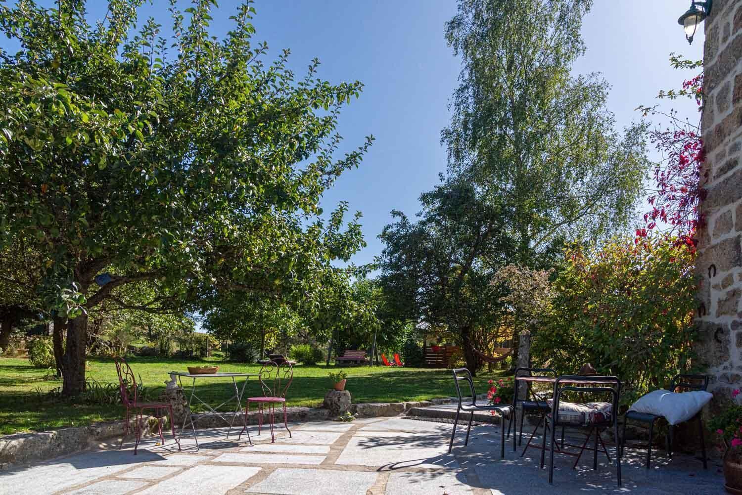 Eine Terrasse mit Gartenmöbeln, einem gepflasterten Weg und üppiger Bepflanzung.