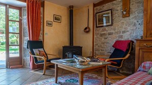A cozy room with a fireplace, a wooden table, two chairs, and a bed. - Gîte La Narce - TERMES (TERMES)