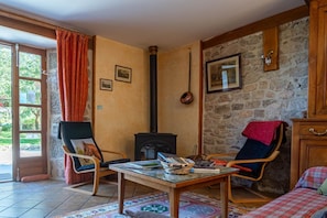 Une pièce chaleureuse avec une cheminée, une table en bois, deux chaises et un lit.