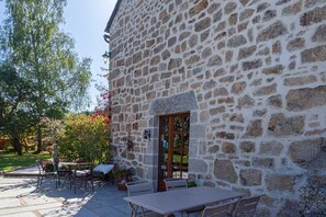 A stone building with a patio area featuring outdoor seating and a table. - Gîte La Narce - TERMES (TERMES)
