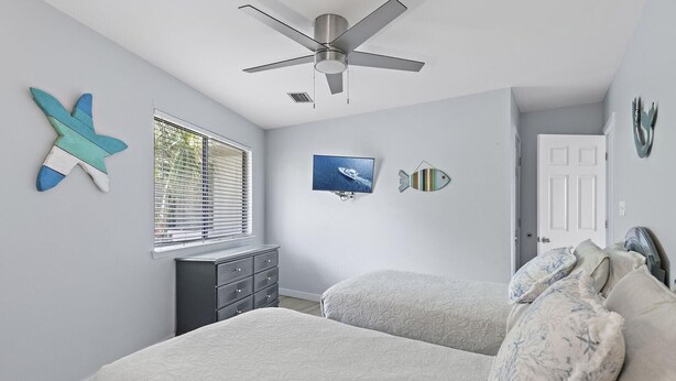 A bedroom with a bed, dresser, ceiling fan, and decorative wall art. - Crystal Village II 8B- Vitamin Sea (Miramar Beach)
