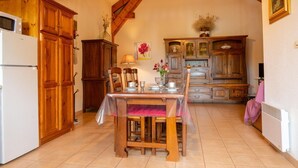 Una cocina con armarios de madera, una mesa de comedor con sillas, un refrigerador y un cuadro en la pared.