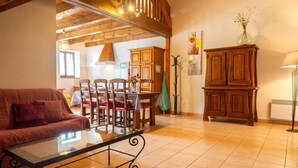 Una sala acogedora con sofá, mesa de comedor, sillas, armarios de madera y una lámpara de pie.