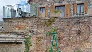 Un edificio de piedra con un balcón, una rueda de bicicleta y un cartel.