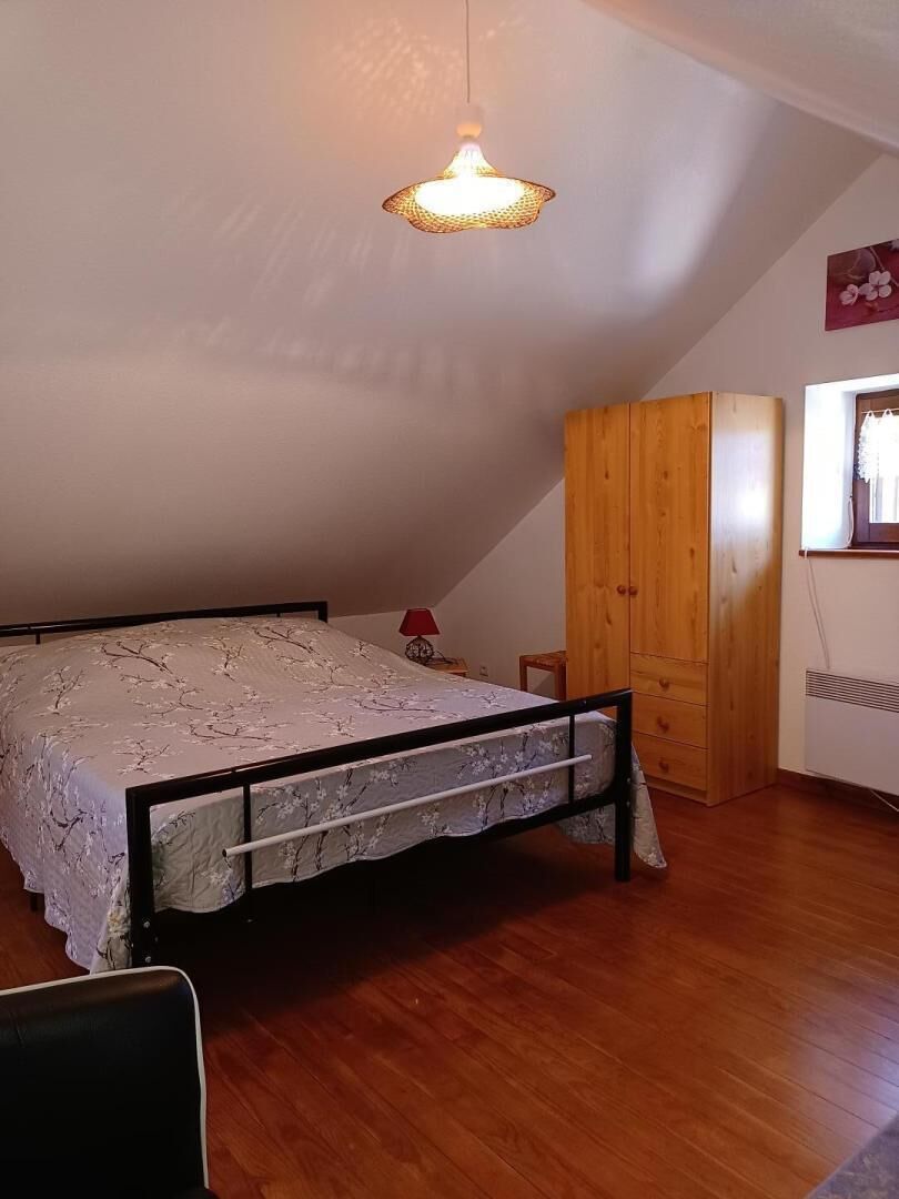 A bedroom with a bed, wooden wardrobe, and a hanging light fixture.