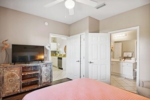 A bedroom with a bed, a TV, a dresser, and a door leading to a bathroom. - Emerald Waters 407- On Beach Time (Miramar Beach)