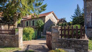 Un bâtiment en pierre avec un toit en tuiles, une porte en bois et une entrée pavée.