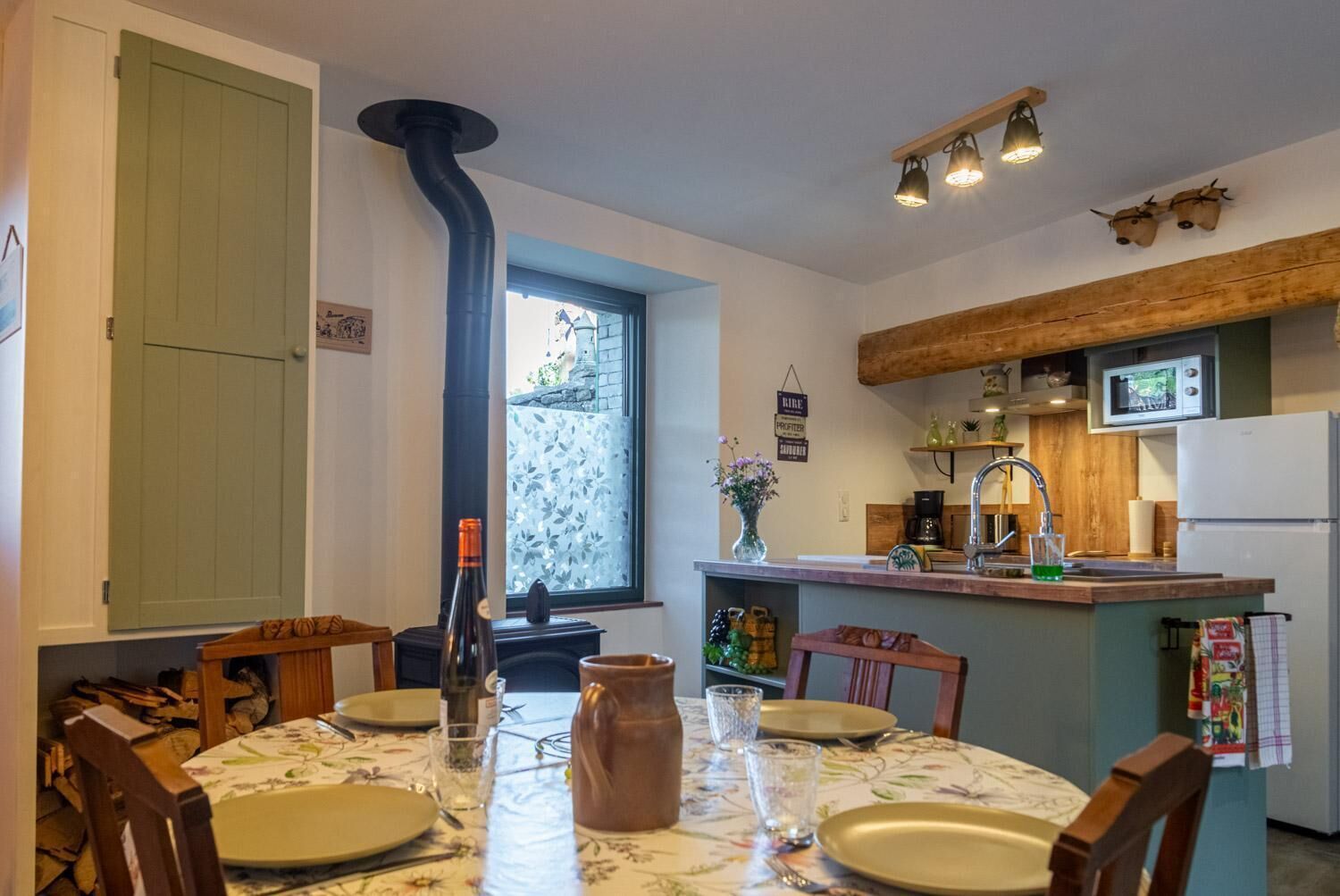 A kitchen with a stove, a dining table set for four, and a window with a view.