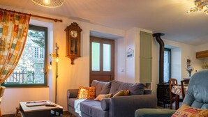 Un salon confortable avec un canapé, une table, une horloge et une vue sur l’extérieur.